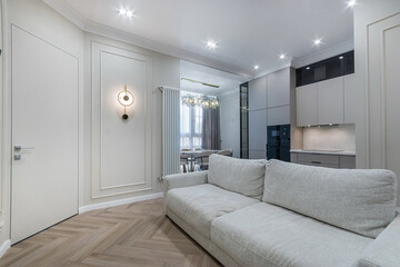 Elegant interior design of the studio apartment, decorated in white. Parquet floors, white furniture and beautiful lamps.