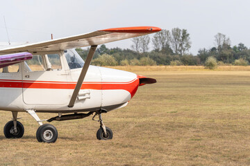 Red and white high-wing small passenger plane at a grassy airport