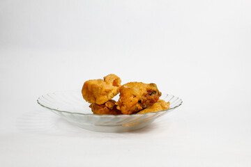 Fried tofu stuffed with vegetables and fried tempeh served in a transparent glass plate, isolated on a white background