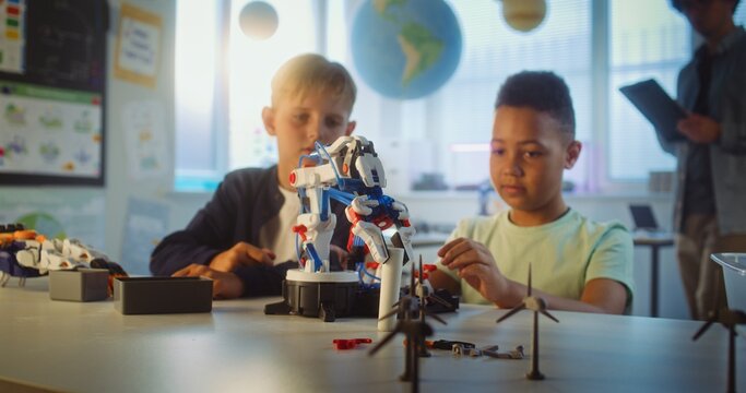 Elementary School Students Studying Model of Innovative Robotic Arm During Science and Engineering Lesson. Diverse Smart Young Boys Sitting at Table in Group in Classroom. Interactive STEM Education. - Powered by Adobe
