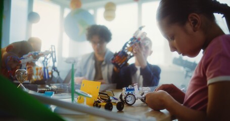Diverse Group of Children and Young Teacher Working Together on STEM Projects in Multicultural Classroom. Elementary School Students Exploring Robotics and Renewable Energy Models, Learning Science.