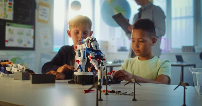 Elementary School Students Studying Model of Innovative Robotic Arm During Science and Engineering Lesson. Diverse Smart Young Boys Sitting at Table in Group in Classroom. Interactive STEM Education. - Powered by Adobe