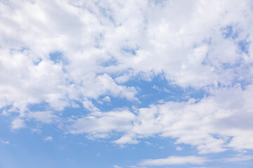 Blue sky background with clouds. Sun shining through the puffy clouds. Sky view. Beautiful sunny...