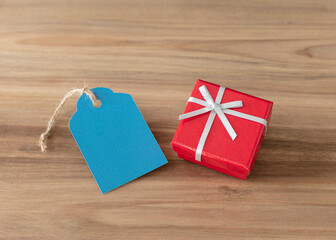 Red close gift box with a blue  tag isolate on wood background.