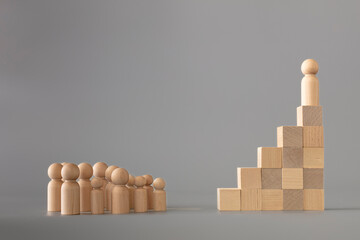 Leader figure standing out from crowd on wooden cubes, other figures in front on floor. Leadership...