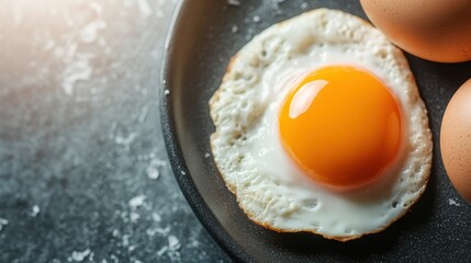 Close-up of a perfectly fried sunny side up egg on a sleek black plate, showcasing the bright yolk and culinary art that captures the essence of breakfast.