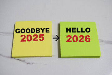 Concept of Goodbye 2025 to Hello 2026 write on sticky notes isolated on Wooden Table.