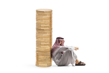 Pensive middle eastern man sitting and leaning on a pile of coins