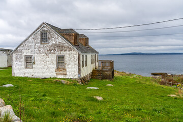 Obraz premium Solitary home needing renovation overlooks the harbour of Peggys Cove near Halifax in Nova Scotia, Canada