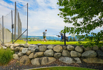 A young man holds the finish after a swing at a suburban golf course.