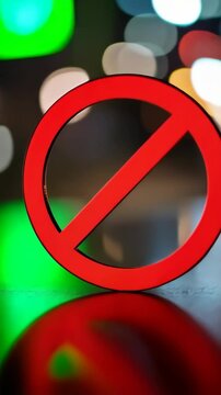 Symbol of a red prohibition sign with a diagonal line through a circle set against a bokeh light background implying warning and restrictions.