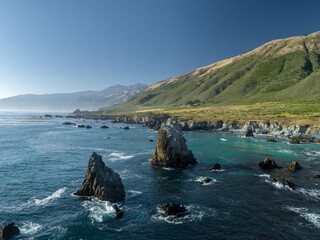 Big Sur coastline, California, USA. Rugged cliffs meet the Pacific Ocean, creating a dramatic landscape. Waves crash against rock formations, showcasing nature's power.