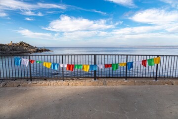 Prayer flags hang on a railing overlooking the Pacific Ocean in Lovers Point Beach, Pacific Grove,...