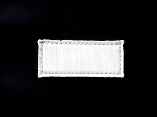 Blank white fabric label with stitched border on black background. Ideal for clothing tag mockups or branding purposes. Generative AI