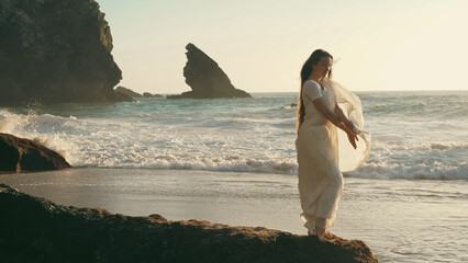 A girl in a sari dances against the backdrop of the ocean at sunset. Meditation.  Yoga. Soft focus