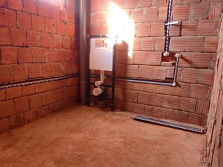 Plumbing installation work. Plastic pipes with thermal insulation in modern design bathroom. Completion of rough work