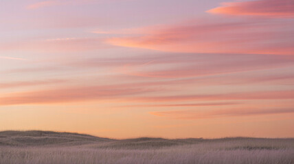 Obraz premium Vibrant sunset paints the sky over a serene landscape with gentle hills and calm atmosphere