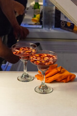 Red Craft Cocktail in Coupe Glass on Bar Counter with People in Background - Nightlife and Happy Hour Scene