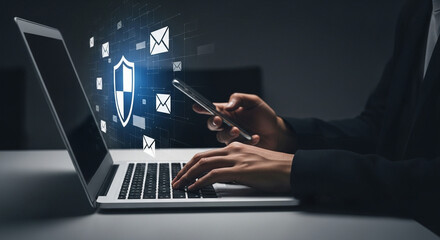 Person using laptop and phone with digital shield and email icons overlayed for cybersecurity