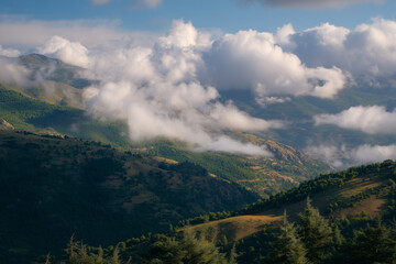 Obraz premium Stunning mountain landscape with clouds rolling over lush green hills