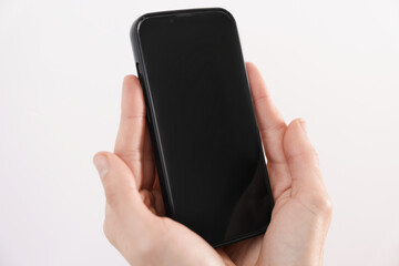 Woman holding smartphone with blank screen on white background, closeup. Mockup for design