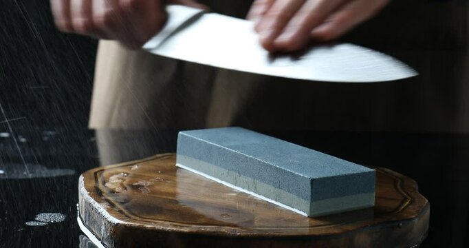 Man sharpening knife with sharpener at mirror table, closeup