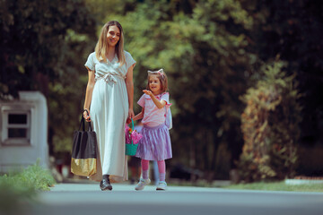 Fototapeta premium Mother and Daughter Going Back to School with a Flower Basket. Parent and child head to kindergarten on the first day of school