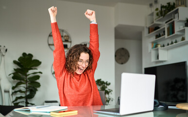 Excited girl winning online, getting approved job opportunity using computer at home. Happy young...