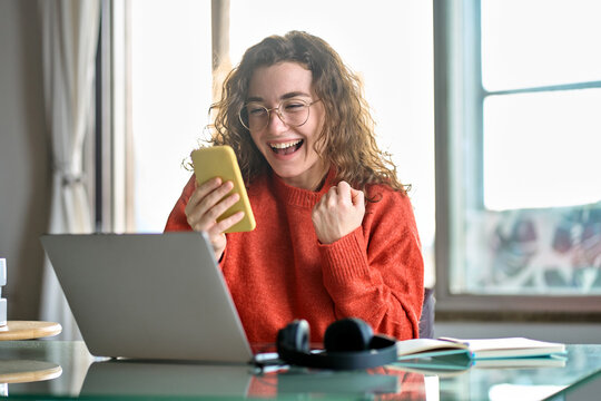 Happy young woman student feeling excited winner holding cellphone using mobile phone winning online, receiving great news or sms offer looking at smartphone, getting new job celebrating success.