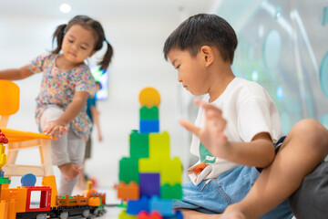 Obraz premium Adorable little child boy and girl playing plastic block toy building imagination