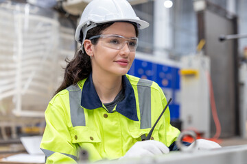 Happy woman engineer worker enjoy working in factory industry. Female engineer wearing safety...