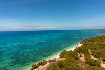 Tropical landscape with sandy beach and turquoise sea surface with coral reef. Bantayan Island, Cebu, Philippines.