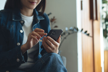 Woman using mobile phone at coffee shop. Smiling asian freelancer, entrepreneur in blue jeans using smartphone, surfing the internet at cafe