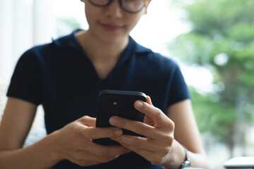 Fototapeta premium Asian woman using smartphone, browsing the internet, social networking on mobile app at home. Woman using mobile phone for online shopping and mobile banking via mobile app, closeup