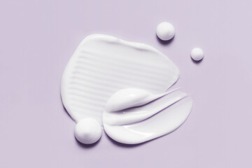 Cosmetic cream smears. White skincare product creamy texture. Lotion swatch on light purple...
