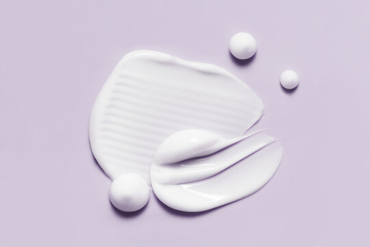 Cosmetic cream smears. White skincare product creamy texture. Lotion swatch on light purple background
