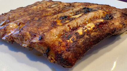 Delicious perfectly grilled pork ribs resting on a white plate