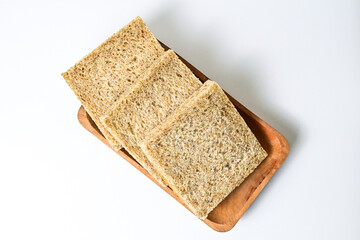 Top view of whole wheat sliced bread on long wooden plate. isolated on white background. clipping path. high angle, above.