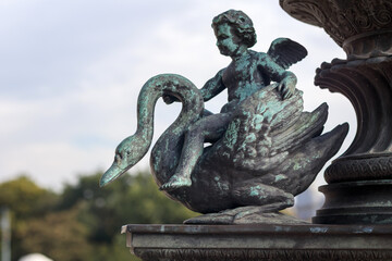 
a bronze statue depicting an angel or cupid sitting on the back of a swan, with the bird's wings...