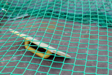 
A bright green, mesh-like material with square meshes is visible, with a blurry yellow-white...