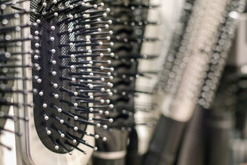 
A row of different types of hairbrushes is visible, mostly black, with metal bristles and round tips of various sizes.