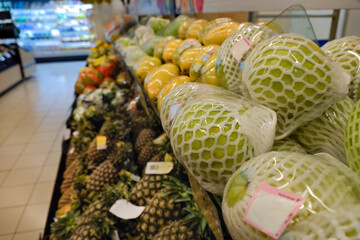 Fresh fruits individually wrapped plastic in produce section, pre-packed. This method to extend shelf life of fresh produce leads to plastic pollution. Plastic waste concept in supermarket.