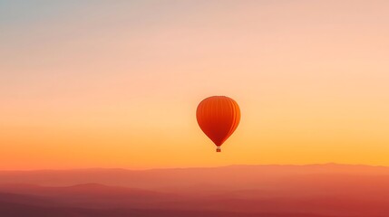 Obraz premium Solitary Hot Air Balloon Ascends Into The Sunrise Over A Hazy Landscape