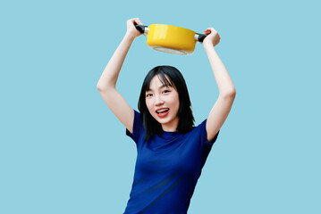 Enthusiastic young woman joyfully holding a yellow pot on a bright blue background while...