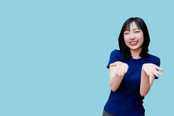 Smiling Asian woman gesturing cheerfully with hands in playful expression against a light blue...