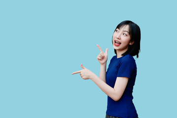 Young Asian woman joyfully gesturing with playful expressions against a light blue background in a...
