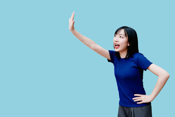 Young woman joyfully expressing herself and waving in a light blue setting during a sunny day