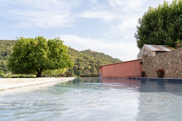 Enjoy a tranquil poolside setting, surrounded by lush green trees and majestic hills against a...