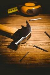 Claw hammer is resting on wooden workbench, flat design showing scattered nails and tape measure