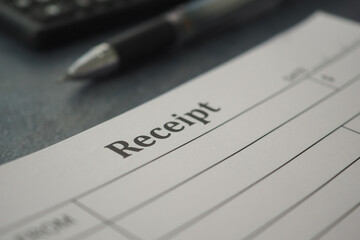 Receipt on a desk with a pen and calculator nearby